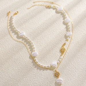 Dettaglio della collana di perle barocche a strati con ciondoli floreali dorati