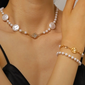 Dettaglio di elegante set di gioielli con collana e bracciale in perle barocche e fiori d'oro