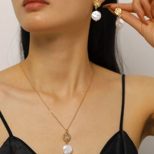 Dettaglio di un set elegante di collana in perle barocche e orecchini a fiore su modella.