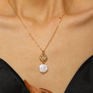 Dettaglio collana con perla barocca, ciondolo floreale dorato e punto luce in cristallo