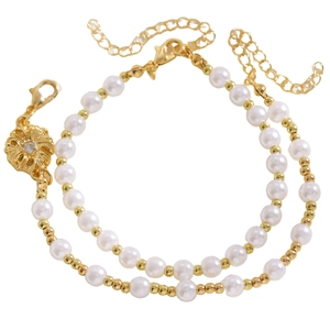 Dettaglio della collana di perle a due fili con ciondolo a fiore dorato e perline.