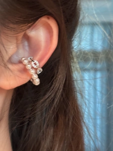 Detailed close-up showing a delicate double-layered pearl and crystal ear cuff worn on the ear.