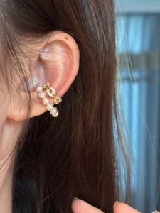 Close-up of a C-shaped ear cuff with pearls and gold zircon links worn on the ear.