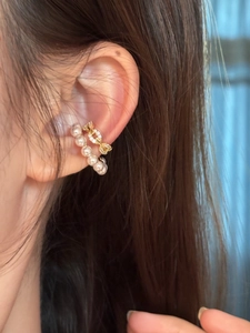 Detailed close-up of stylish zircon and pearl C-shaped ear cuffs on an ear model