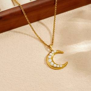 Primo piano di una collana in acciaio inossidabile dorato con pendente a luna e perle.