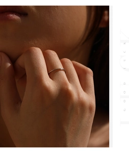 Detailed close-up of a minimalist moissanite sterling silver ring on a model's finger