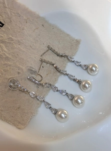 Detailed macro shot of long drop earrings featuring cubic zirconia and elegant pearls