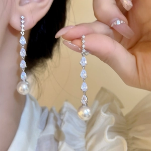 Elegant close-up view of long zircon and pearl drop earrings with silver finish