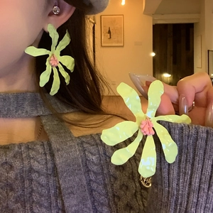 Close-up detail of lime green flower earrings with pink centers for a summer look
