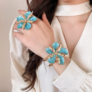 Primer plano de anillo y brazalete de flores en esmalte azul en la muñeca de una modelo