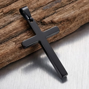 Detail view of matte black stainless steel cross pendant on rustic wood background