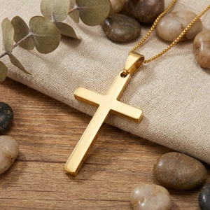 Close-up of a minimalist gold stainless steel cross necklace on linen cloth.