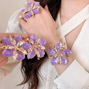 Elegante conjunto de joyas de flores de esmalte morado y dorado llevado por una modelo, detalle