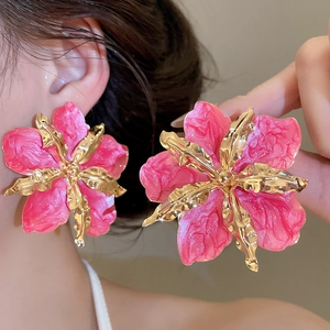 Detalle de pendientes de flores de esmalte rosa con detalles dorados en una modelo