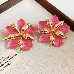Detalle de cerca de pendientes de flor en esmalte rosa y oro con diseño vintage texturizado