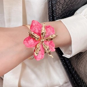 Primer plano de un brazalete metálico con flor de esmalte rosa estilo vintage