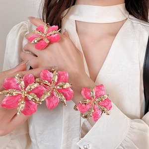 Primer plano de conjunto de joyas vintage con flores de esmalte rosa en anillo y pulsera.