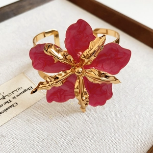 Detalle de brazalete vintage de flor esmaltada en rojo con detalles metálicos dorados