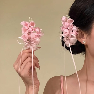 Detailed view of sweet pink fabric flower hair clip with elegant ribbon tassels on model