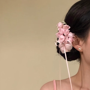Detail view of sweet pink floral hair clip with ribbons on woman bun hairstyle