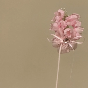 Close-up of pink fabric flower hair clip with delicate ribbon and rhinestone detail