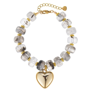 Detailweergave van een kralenarmband van hars met een glanzende gouden harthanger