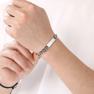 Detail view of a minimalist silver stainless steel bar bracelet with a curb chain on wrist.