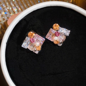 Gedetailleerde weergave van geometrische oorknopjes met strass en kleine parel