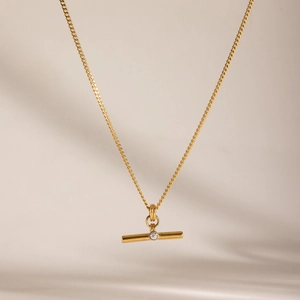 Detail of gold stainless steel T-bar pendant necklace with a central white rhinestone
