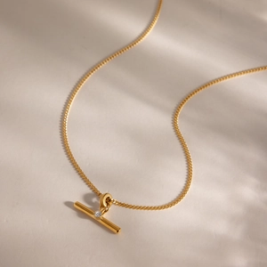 Detail view of golden stainless steel T-bar necklace with sparkling white rhinestone.