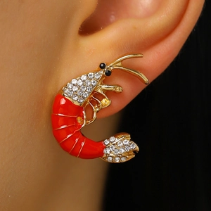 Detailed close-up of a red enamel lobster earring with sparkling rhinestones on the ear.