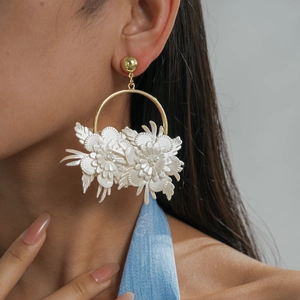 Elegant white leather flower hoop earring detail worn by model for a stylish look.