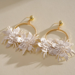 Close-up of elegant gold hoop earrings featuring white leather flowers and pearls.