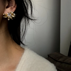 Elegant gold floral stud earrings featuring cubic zirconia stones worn by an Asian model