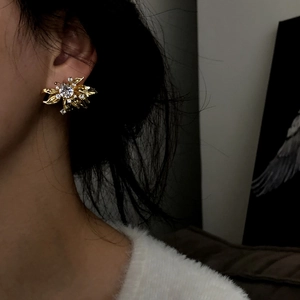 Close-up view of elegant French style gold flower stud earrings with zircons on ear