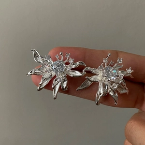Detailed macro view of elegant silver-tone floral stud earrings with sparkling clear zircons