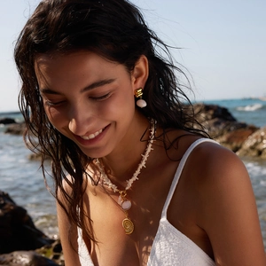Luxury titanium steel seashell necklace set worn by model on a sunny beach background