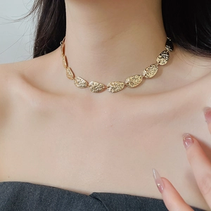Nahaufnahme einer goldenen Vintage-Halskette mit Hammerschlag-Metallblättern am Hals