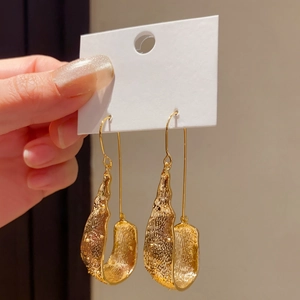 Macro view of vintage gold U-shaped drop earrings featuring a unique hammered texture.