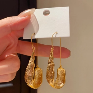 Detailed macro shot of vintage gold U-shaped drop earrings featuring a unique textured finish