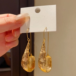 Close-up of gold U-shaped drop earrings with hammered texture on a white card.
