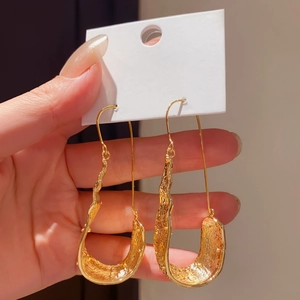 Detailed view of textured gold U-shaped drop earrings with a vintage molten finish