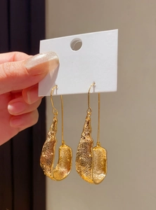 Detail shot of vintage-style gold U-shaped drop earrings with a rich melted metal texture