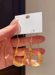 Close-up showing the intricate textured surface of gold retro U-shaped drop earrings