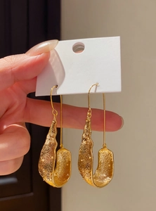 Macro view of vintage gold U-shaped drop earrings with hammered texture finish
