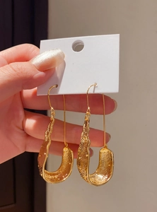 Close-up of retro textured gold U-shaped dangle earrings presented on white card