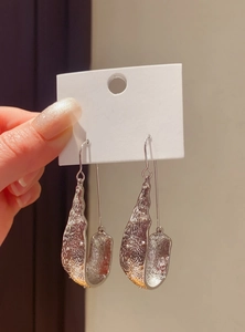 Close-up of vintage silver U-shaped drop earrings with textured molten metal surface.