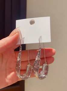 Close-up of elegant silver-toned textured U-shaped dangling hook earrings with a vintage finish