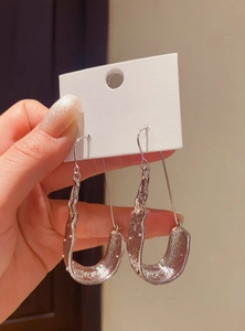 Detail view of silver U-shaped dangle earrings with a textured molten lava finish.