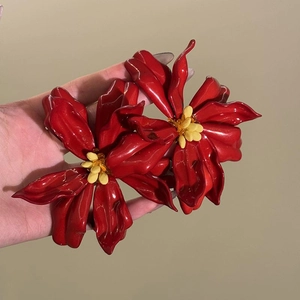 Detailed view of red acrylic flower stud earrings with glossy petals and yellow center beads